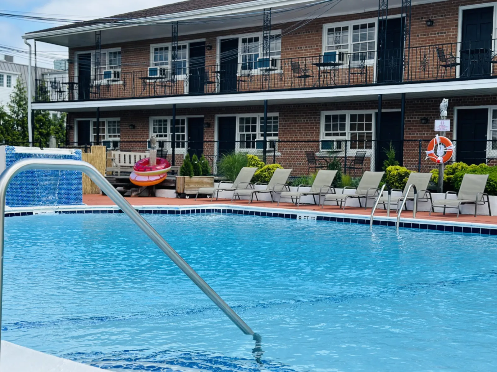 Outdoor pool with lounge chairs and brick motor-court building